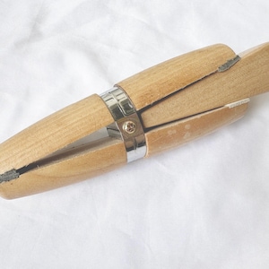 Puede incluir: Un mandril de anillo de madera con una banda de metal y un tornillo. El mandril se utiliza para dimensionar y dar forma a los anillos.