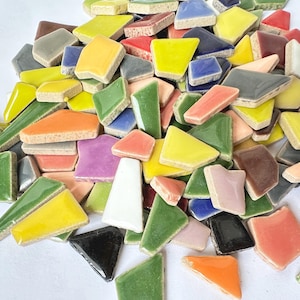 Puede incluir: Un mont&oacute;n de azulejos de mosaico de cer&aacute;mica de colores en varias formas y tama&ntilde;os. Los azulejos son en tonos de verde, amarillo, naranja, rojo, marr&oacute;n, morado, rosa, blanco y negro.
