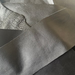 May include: Close-up of three pieces of black leather with a textured surface.