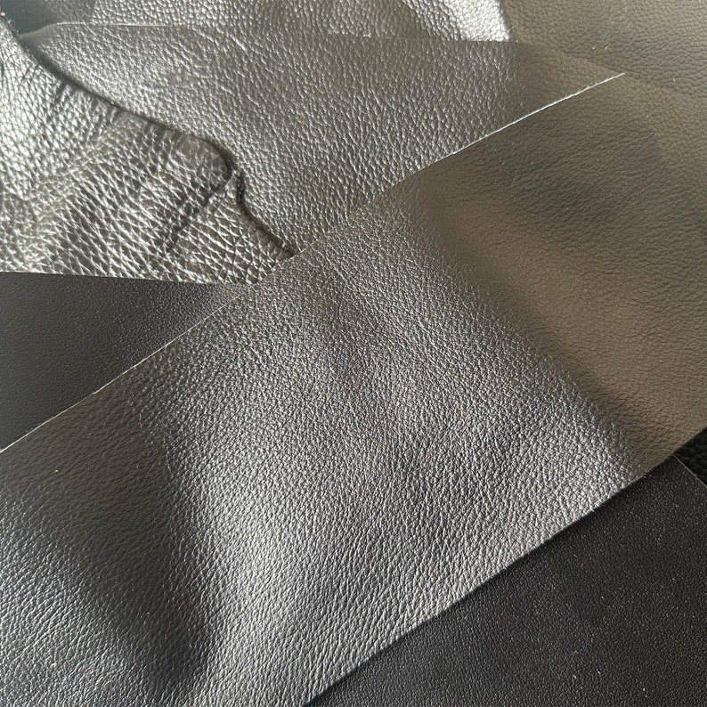 May include: Close-up of three pieces of black leather with a textured surface.