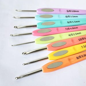 May include: A set of 10 colourful crochet hooks with silver metal tips. The hooks are labelled with their size and corresponding millimetre measurement. The sizes are 5/0 3.0mm, 6/0 3.5mm, 9/0 5.5mm, 7/0 4.0mm, 4/0 2.5mm, 10/06, 7.5/, and 8/0 5.00.