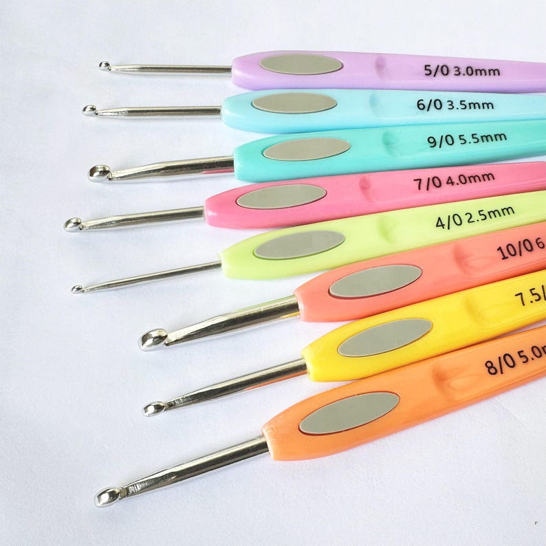 May include: A set of 10 colourful crochet hooks with silver metal tips. The hooks are labelled with their size and corresponding millimetre measurement. The sizes are 5/0 3.0mm, 6/0 3.5mm, 9/0 5.5mm, 7/0 4.0mm, 4/0 2.5mm, 10/06, 7.5/, and 8/0 5.00.