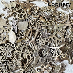 May include: A large collection of antique-looking metal charms in various shapes and sizes. The charms are made of a coppery metal and have a distressed finish. Some of the charms include a star, a flower, a key, a horseshoe, a leaf, and a bird. The charms are perfect for adding a vintage touch to jewelry, crafts, and other projects.