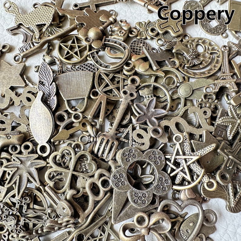 May include: A large collection of antique-looking metal charms in various shapes and sizes. The charms are made of a coppery metal and have a distressed finish. Some of the charms include a star, a flower, a key, a horseshoe, a leaf, and a bird. The charms are perfect for adding a vintage touch to jewelry, crafts, and other projects.