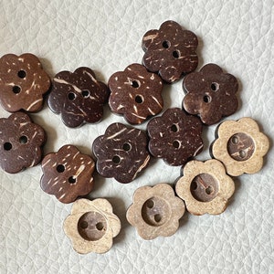 May include: A collection of 12 brown and natural coconut shell buttons in a flower shape with two holes each.