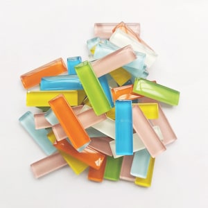 May include: A pile of colorful glass tiles in various shades of blue, green, yellow, orange, and pink. The tiles are rectangular and have a glossy finish.