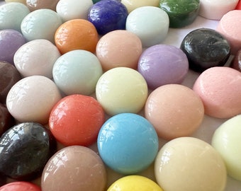 Op de afbeelding: Assortiment van ronde, gladde glazen tegels in verschillende kleuren, waaronder wit, roze, lichtblauw, lichtgroen, lichtgeel, oranje, paars en bruin.