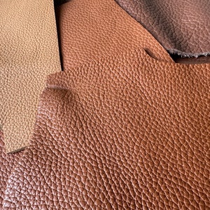May include: Close-up of three different shades of brown leather. The leather has a textured, pebbled surface.