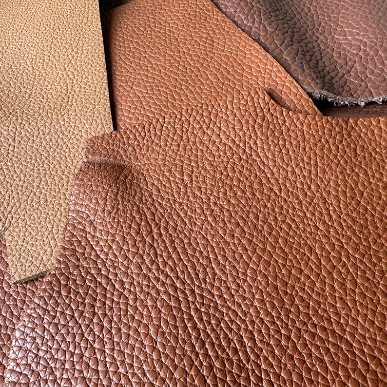 May include: Close-up of three different shades of brown leather. The leather has a textured, pebbled surface.
