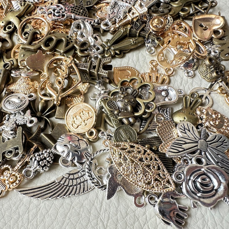 May include: A large assortment of silver and gold-toned metal charms, including hearts, crowns, butterflies, and flowers. The charms are perfect for jewelry making, scrapbooking, and other craft projects.