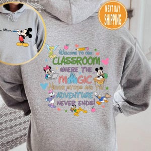 May include: Gray hooded sweatshirt with a colorful graphic featuring Mickey Mouse and other Disney characters. The graphic says "Welcome to our classroom where the magic never stops and the adventure never ends!"