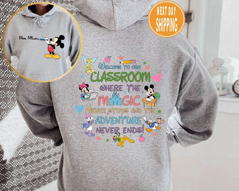 May include: Gray hooded sweatshirt with a colorful graphic featuring Mickey Mouse and other Disney characters. The graphic says "Welcome to our classroom where the magic never stops and the adventure never ends!"