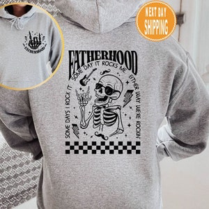 May include: Gray hooded sweatshirt with a black skeleton graphic and the text "Fatherhood: Some days I rock it, some day it rocks me, either way we're rockin'"