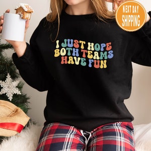 May include: Black sweatshirt with a rainbow colored graphic that says "I just hope both teams have fun".