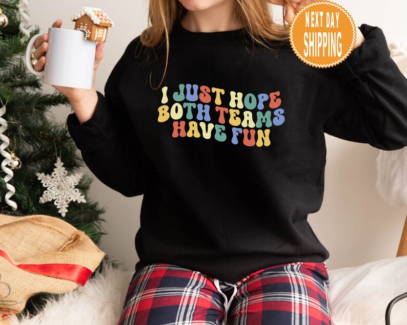May include: Black sweatshirt with a rainbow colored graphic that says "I just hope both teams have fun".