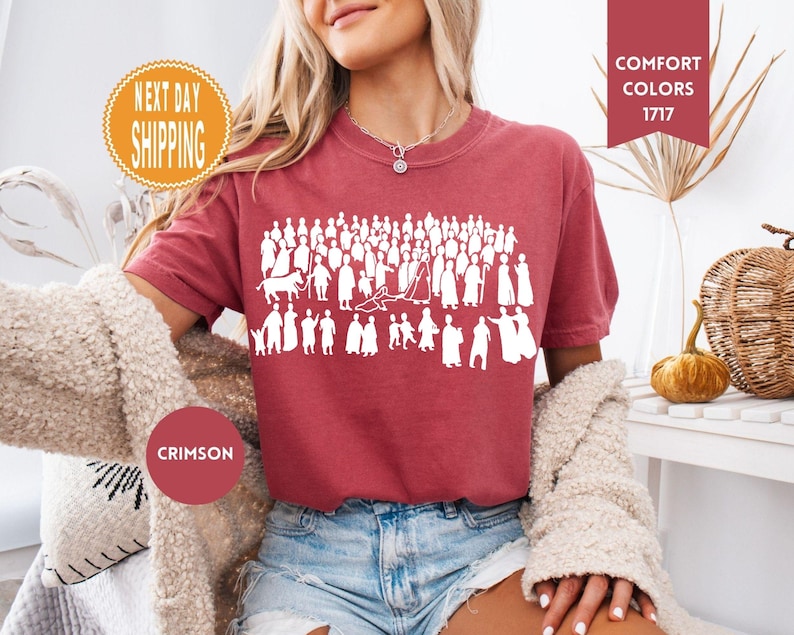 May include: Crimson-colored t-shirt featuring a white graphic of numerous figures. The shirt has short sleeves and is made of a soft material. The image also includes text that says "Comfort Colors 1717".