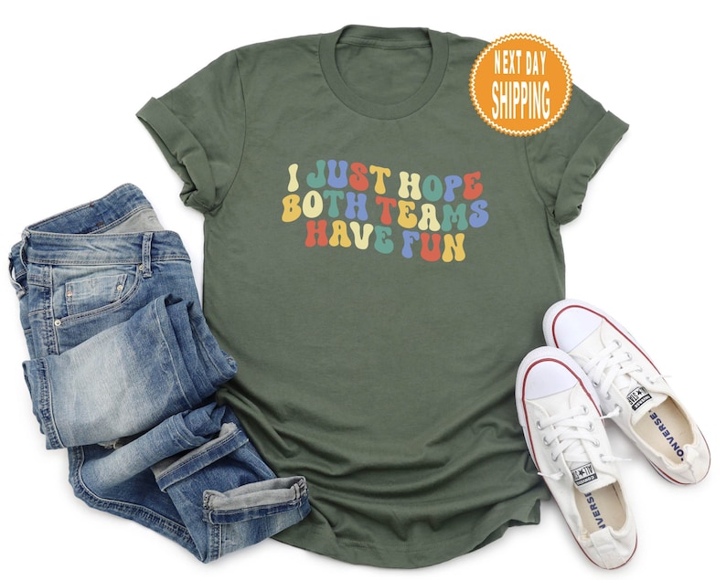 May include: A green t-shirt with the text "I just hope both teams have fun" in colorful retro font.