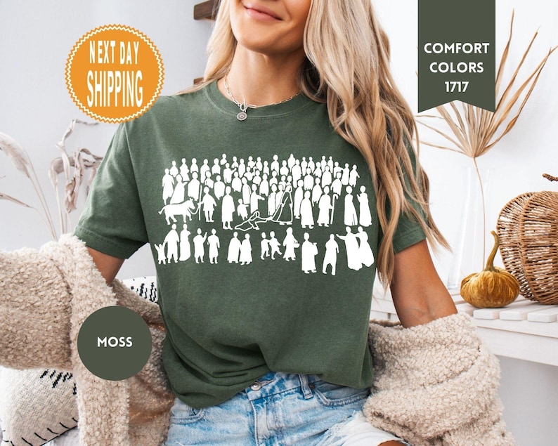 May include: Moss green t-shirt with a white graphic of a crowd of people and animals. The shirt has the words "Comfort Colors 1717" printed on it. The shirt is made of a soft material.