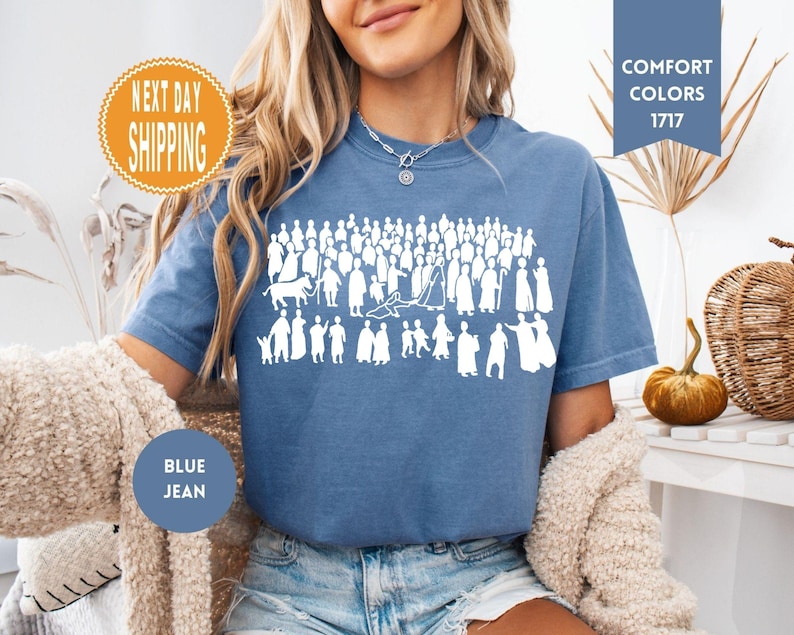 May include: Blue jean-colored t-shirt with a white graphic of a crowd of people. The shirt has the words "Comfort Colors 1717" on a blue banner. An orange circle with the words "Next Day Shipping" is also visible.