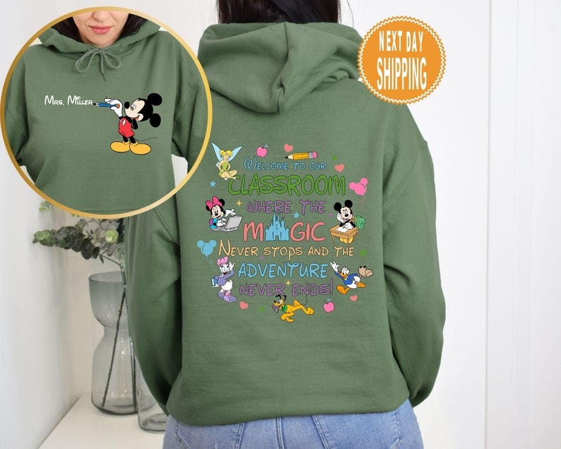 May include: Green hooded sweatshirt with a Mickey Mouse design on the front and a Disney-themed classroom quote on the back. The quote reads "Welcome to our classroom where the magic never stops and the adventure never ends!"