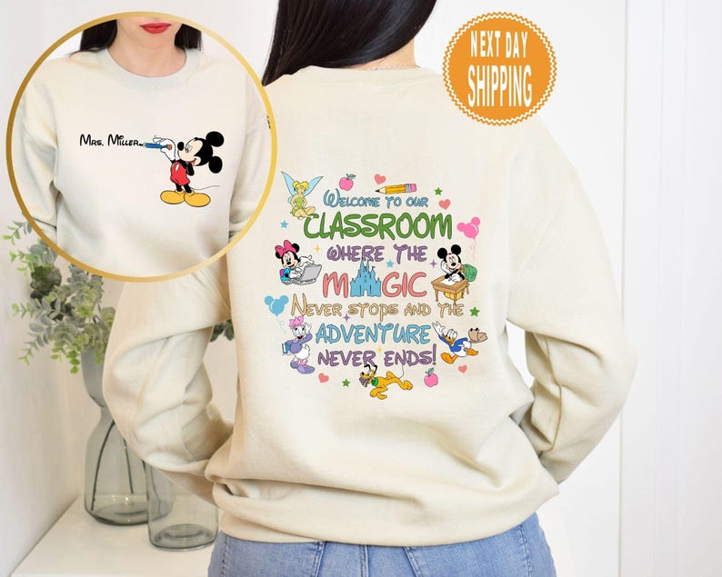 May include: A cream-colored sweatshirt with a Mickey Mouse design and the text "Welcome to our classroom where the magic never stops and the adventure never ends!" printed on the front.