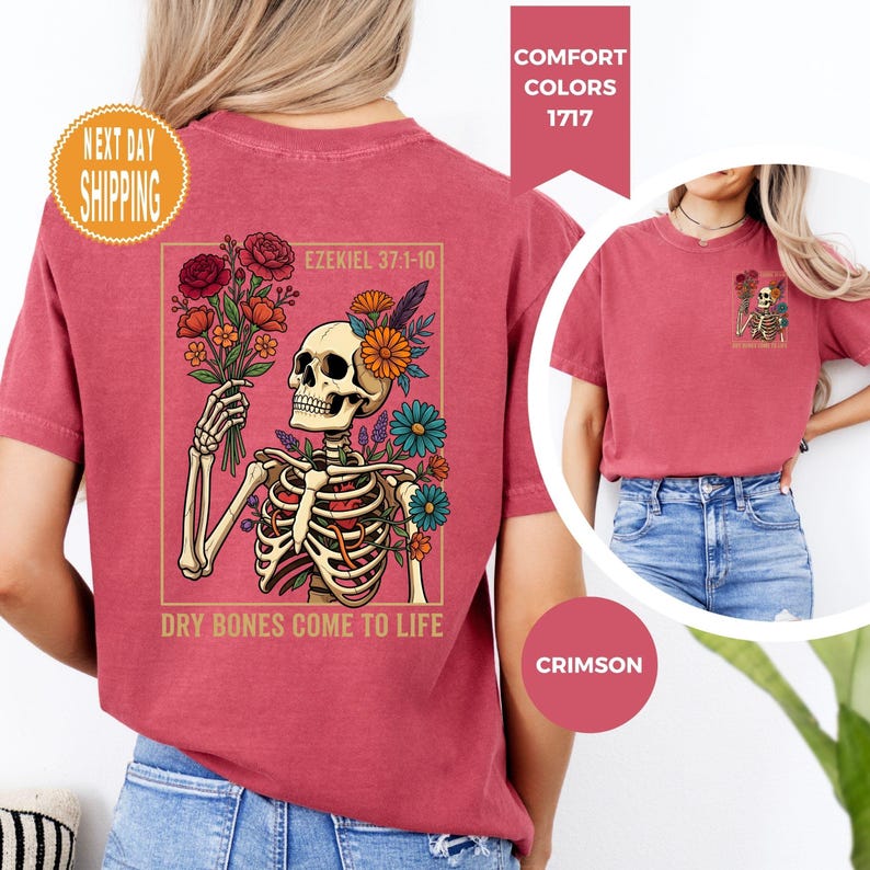 May include: Crimson-colored t-shirt featuring a skeleton holding a bouquet of flowers, with the text "DRY BONES COME TO LIFE" and "EZEKIEL 37:1-10". The shirt has a graphic design of a skeleton with flowers and is a comfort color.