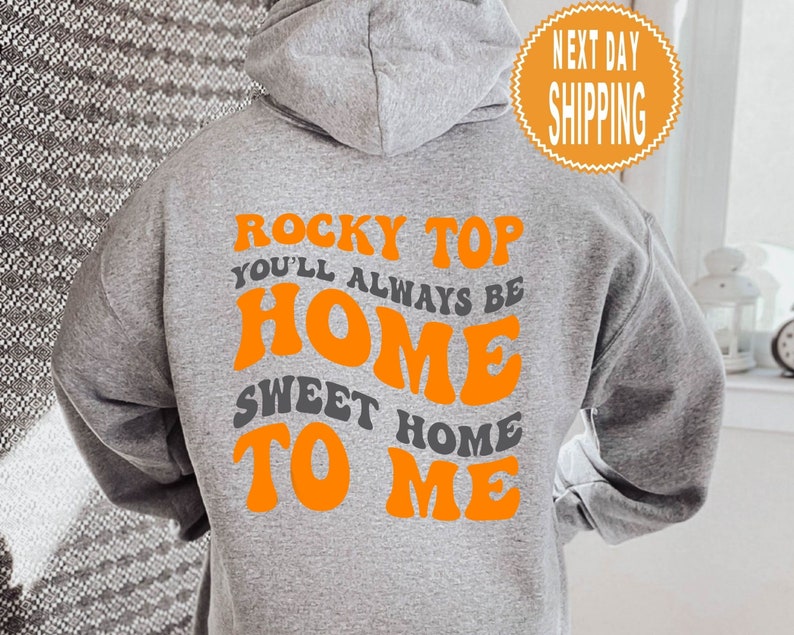 May include: Grey hooded sweatshirt with the text "Rocky Top You'll Always Be Home Sweet Home To Me" in orange letters.