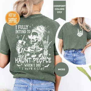 K&ouml;nnte beinhalten: Moosgr&uuml;nes T-Shirt mit wei&szlig;er Grafik eines Skeletts mit Brille, einem Getr&auml;nk und einer Rock-on-Geste. Der Text lautet: "I FULLY INTEND TO HAUNT PEOPLE WHEN I DIE I HAVE A LIST."