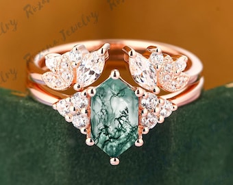 May include: A rose gold ring set with a green moss agate gemstone and accented with small clear stones. The ring is set in a delicate floral design.