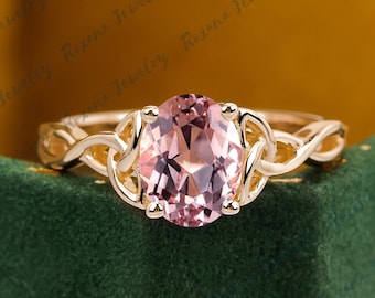 May include: A rose gold engagement ring with a delicate, intertwined band design. The center stone is a large, oval-shaped pink gemstone.