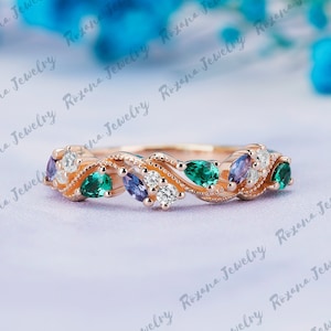 May include: A delicate rose gold band with a floral design featuring emerald green, amethyst, and white round gemstones.