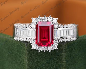May include: A silver ring with a large emerald-cut ruby surrounded by smaller diamonds. The band is set with baguette-cut diamonds.