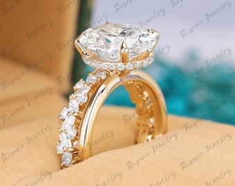 May include: A gold engagement ring with a large, square-cut clear gemstone. The ring features a halo of smaller stones around the main stone and additional stones along the band. The ring is displayed in a jewelry box.