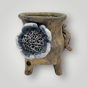 May include: A white ceramic mug with a black handle and the text "But First, Coffee" in a bold, black font. The mug is sitting on a wooden surface. The mug is approximately 4 inches tall.