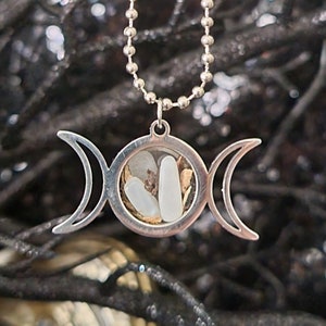 May include: Silver triple moon pendant necklace with a clear glass orb containing white and gold crystals.