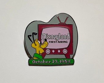 May include: A yellow cartoon dog with floppy ears watches a red and white television with the text "Disneyland First Airing" and "October 27, 1954" on it.