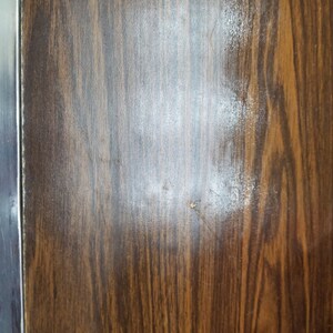 May include: A close-up of a dark brown woodgrain surface with a light brown stain.