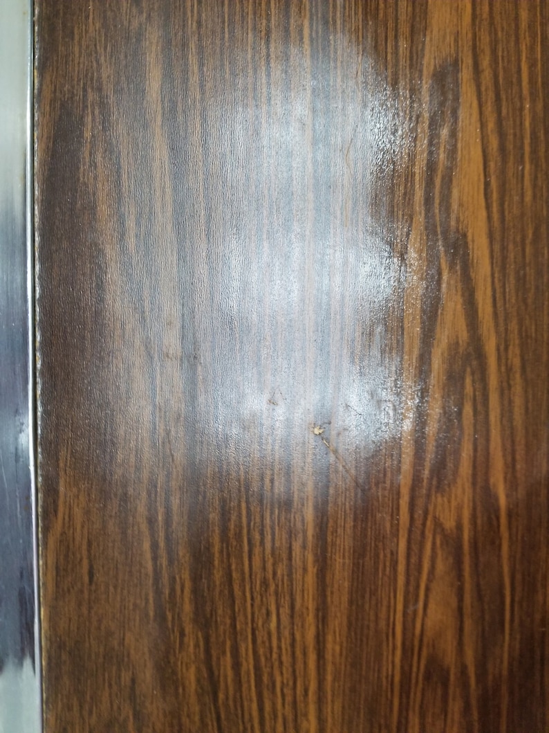 May include: A close-up of a dark brown woodgrain surface with a light brown stain.