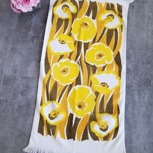 May include: White bath towel with a fringe border and a pattern of yellow flowers on brown stems.