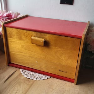 May include: A red and wood bread bin with a wooden handle and the word "Barcraft" printed on the front.