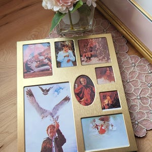 May include: A gold-coloured multi-photo frame displaying several family photographs. The frame has seven picture slots of varying sizes. A bouquet of pink and white flowers is in a glass vase in the background.