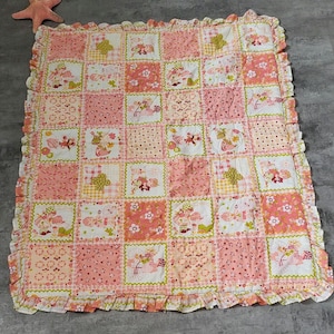 Peut inclure: Une courtepointe patchwork rose et verte avec un bord festonné. La courtepointe présente un motif répétitif de petites fleurs et une fille à vélo.