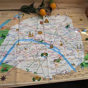 Puede incluir: Un mapa del sistema de metro de París de estilo vintage, impreso en una tela de color crema. El mapa presenta una red detallada de líneas y estaciones, con varios puntos de referencia e interés destacados. El mapa está titulado "Metro" e incluye el texto "Ligne de Sceaux".