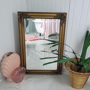May include: A white ceramic mug with a black handle and the text "But First, Coffee" in a bold, black font. The mug is set against a blurred background, suggesting a cozy setting.