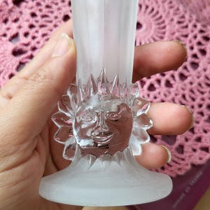 Könnte beinhalten: Eine gefrostete Glasvase mit einem klaren Glas-Sonnengesichtsdesign. Die Vase hat einen breiten Boden und einen schmalen Hals.