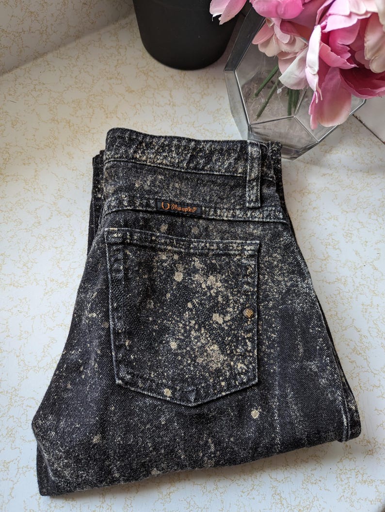 May include: Black acid wash jeans with a brown "Guess" logo on the back pocket.