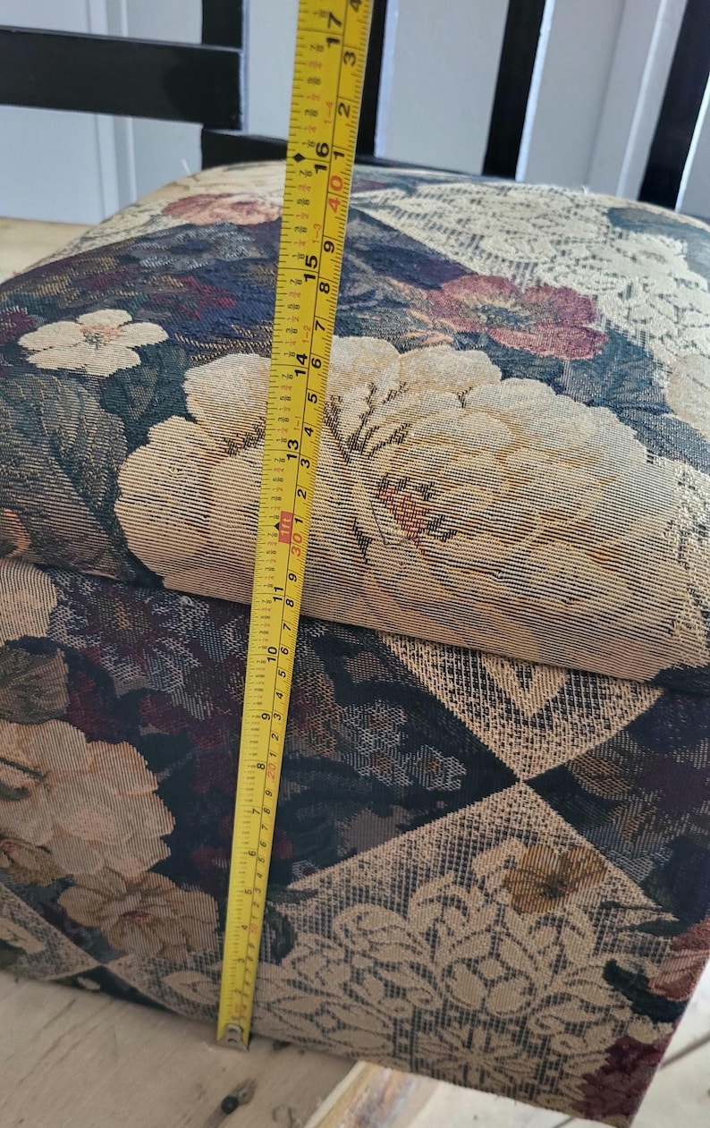 May include: A floral patterned fabric storage box with a yellow measuring tape next to it. The tape measures 17 inches.