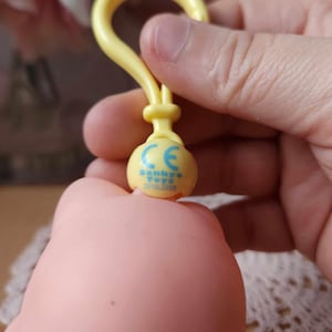 Puede incluir: Llavero de pl&aacute;stico amarillo con un logotipo azul y blanco que dice "Sankyo Toys CE 2018/2088".