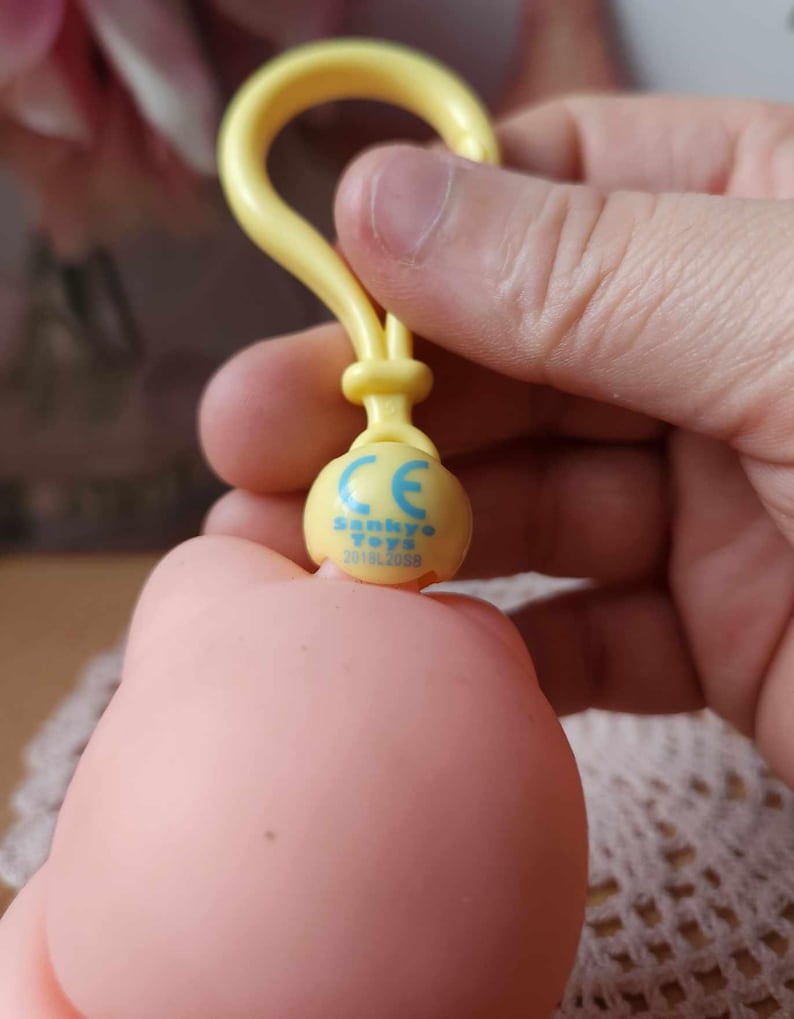 Puede incluir: Llavero de pl&aacute;stico amarillo con un logotipo azul y blanco que dice "Sankyo Toys CE 2018/2088".