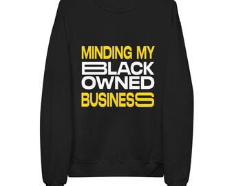 May include: A black long-sleeve sweatshirt featuring the yellow and white text "MINDING MY BLACK OWNED BUSINESS" printed on the front. The design uses a bold, sans-serif font with the word "BLACK" and "OWNED" in white, while the other words are yellow.